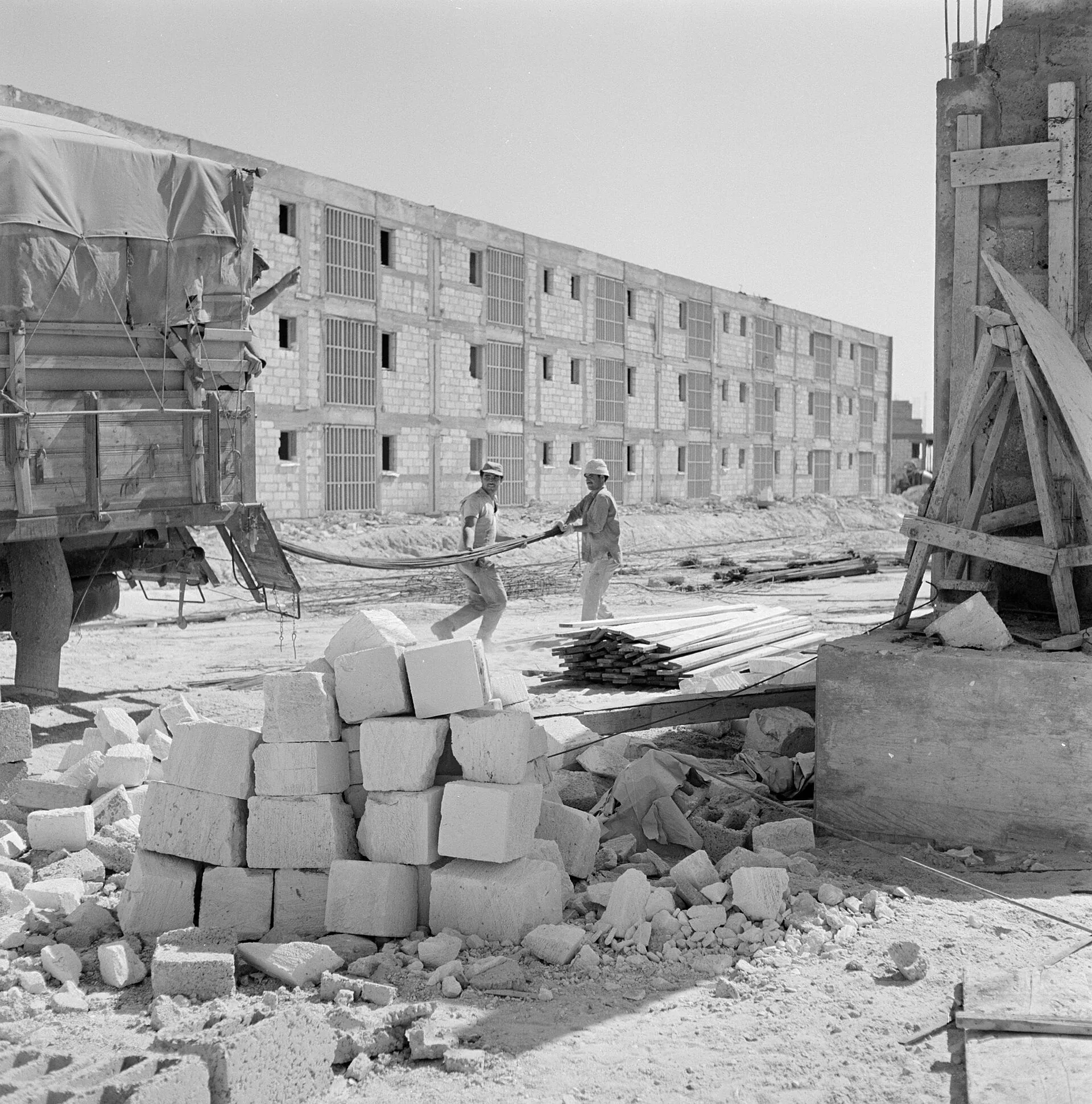 Stacks of building blocks on a housing site, with block-walled flats behind