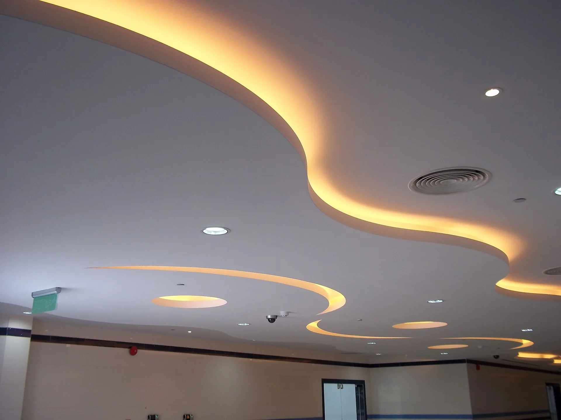 Curved gypsum false ceiling with cove lighting and downlights