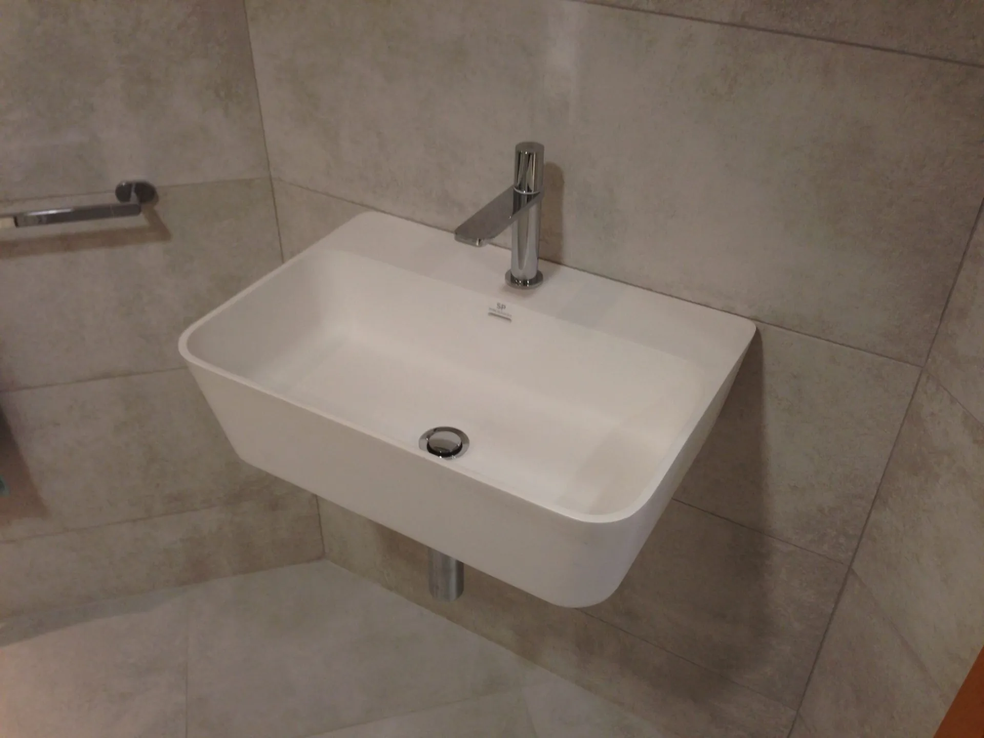 Wall-mounted white wash basin with a chrome tap